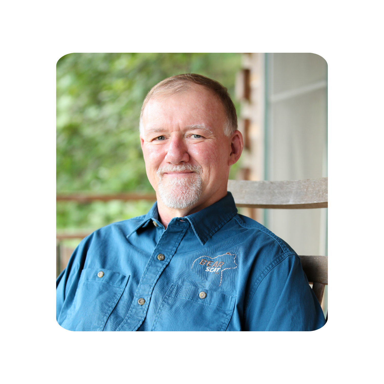 Frank, owner of BearScat LLC, smiling while seated in a chair wearing a blue polo shirt